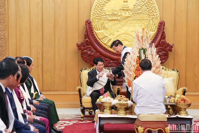 梁强主席参加老挝栓线祈福仪式。图为通伦·西苏里主席为梁强主席系上线。