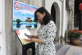 游客扫描二维码，体验在都祠遗迹实现数字化的参观行程。（图片来源：越通社）