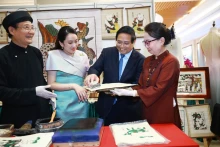 范明正总理与泰国总理佩通坦参观了解越南东胡画制作工艺。（图片来源：越通社）