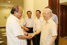 阮富仲总书记与与会的中央政治局委员、中央书记处书记握手。