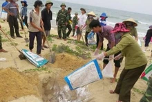 附图：渔民和边防部队收集并掩埋被冲上岸的死鱼。