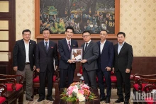 越南《人民报》社总编辑黎国明向朝鲜驻越南大使李成国送纪念品。