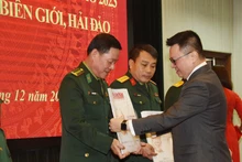《人民报》社总编辑黎国明向战士们赠送春节特刊。