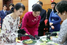 两位夫人一起体验制作河内传统饼点扁米饼。（图片来源：越通社） 