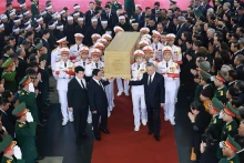 党和国家领导人将阮富仲总书记灵柩抬上灵车，送别总书记到安息之地。