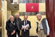 越南驻法国大使丁全胜阅读《巴黎圣母院塔尖上的越共旗帜》一书。（图片来源：越通社）