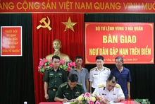 海军第三区司令部和山茶边防屯的代表签署并交接了两名遇险渔民。（图片来源：人民军队报）