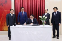 越南政府总理范明正在吊唁簿上签名留言。