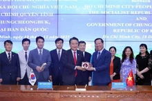 胡志明市人民委员会主席潘文买向韩国忠清北道知事金荣焕赠送纪念品。 