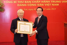 越共中央书记处常务书记武文赏代表党领导向越共中央总书记阮富仲授予党龄55年徽章。