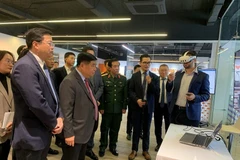 政府副总理阮志勇和其他代表听取关于人工智能与数字孪生研发中心及卓越中心的报告。（图片来源：人民军报网）