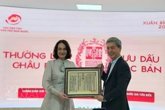 越南国家文书与档案局局长邓青松向俄罗斯驻越大使夫人埃琳娜·贝兹德特科赠送一幅越南国号的木刻版画。（图片来源：越通社）