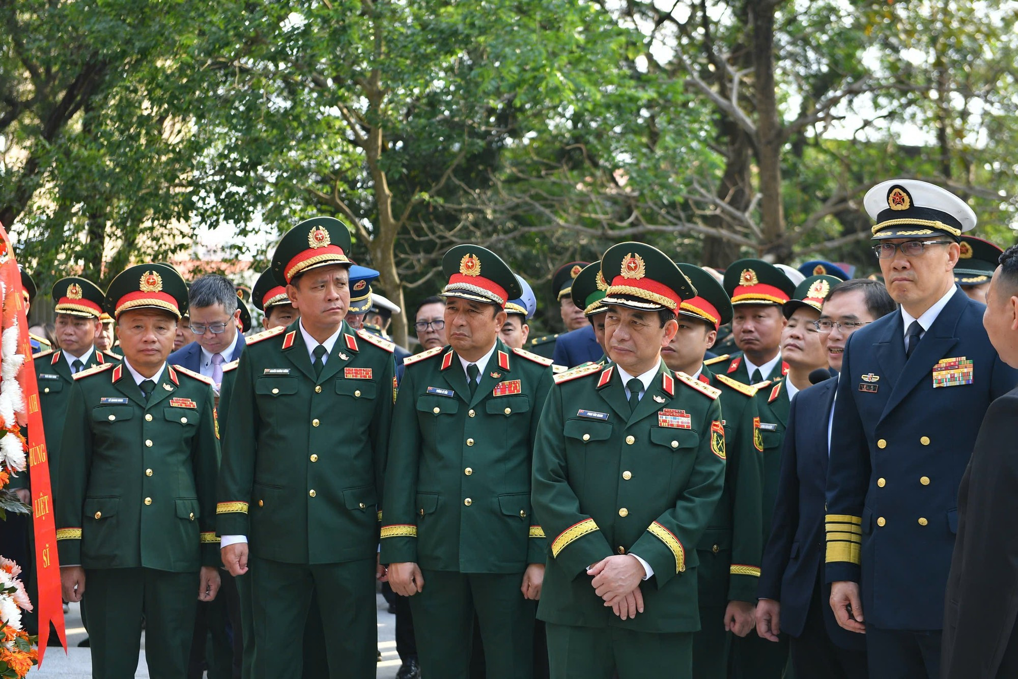 潘文江大将与董军上将以及两国各位代表倾听关于越中人民革命烈士纪念碑的介绍。