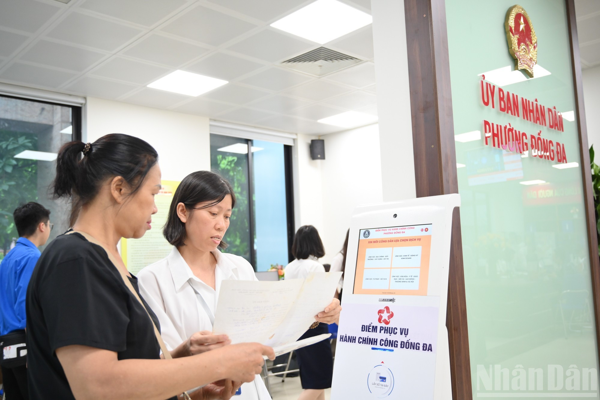 信息技术人员正在配置新的居民数据和行政区划系统，并在“一站式服务”窗口指导市民进行查询操作。