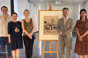 越南驻法国大使郑德海、保罗·艾吕雅艺术与历史博物馆馆长瓦莱丽·佩尔莱斯和越南代表团在《和平万岁》（Vive la Paix）画作原稿旁边合影。（图片来源：越通社）