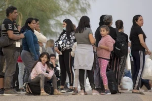 2022年10月10日，在美国德克萨斯州鹰关市的一个检查站，寻求庇护的移民等待登上巴士。（图片来源：新华社）