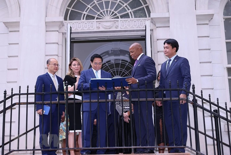 越南政府总理范明正在纪念簿上留言。（图片来源：越通社）