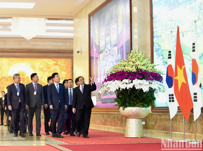 范明正总理向韩国国会议长金振杓介绍越南风土人情的图片。