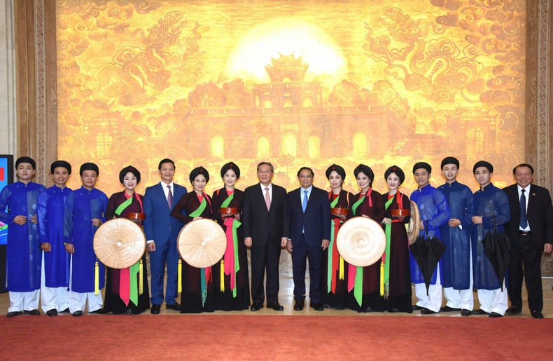 越南政府总理范明正和中国国务院总理李强同北宁官贺民歌艺术家合影。