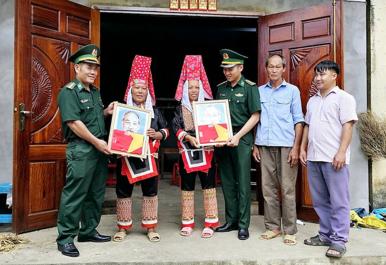 广宁省边防部队向广宁省平辽县横模乡人民赠送胡伯伯的照片与旗子。