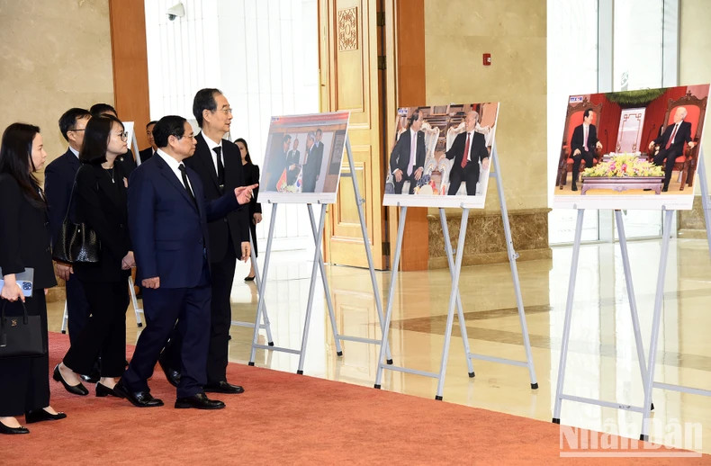 越南政府总理范明正向韩国国务总理韩德洙介绍已故总书记阮富仲对外活动的一些图片。