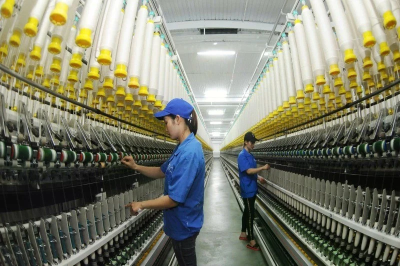 3·8纺织公司工人正在操作纱线生产线。（陈海 摄）