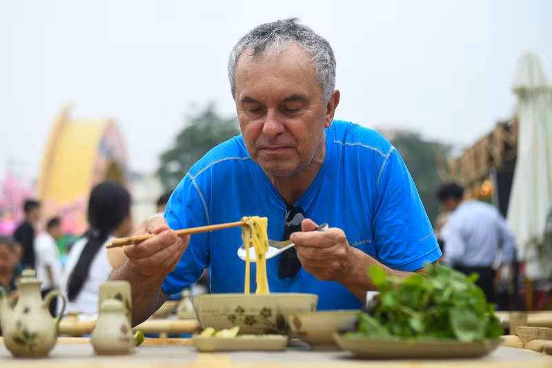 外国游客品尝河江省岩石高原的玉米河粉。