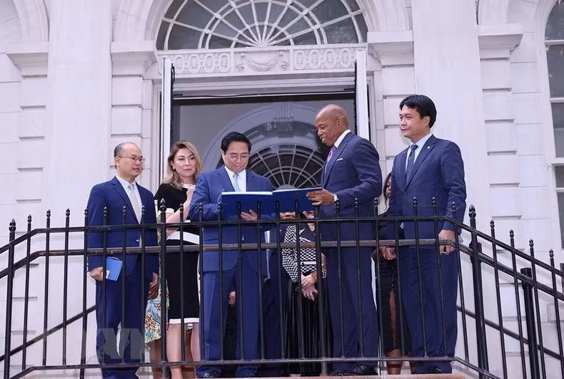 越南政府总理范明正在纪念簿上留言。（图片来源：越通社）