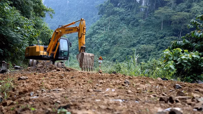 林平县建设投资项目管理委员会动用挖掘机平整道路上的侵蚀点。