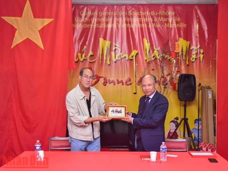 丁全胜大使向旅居马赛越南人协会赠送由法国邮政发行的纪念胡志明主席赴法国100周年邮票图。