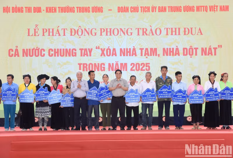 范明正总理和越南祖国阵线中央委员会主席杜文战向贫困家庭代表发放资助资金。