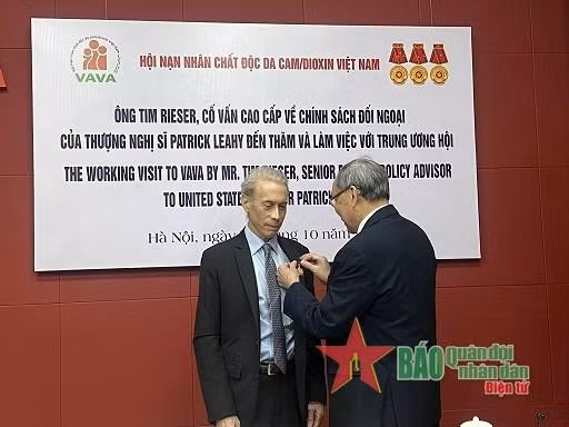 阮文赢上将向蒂姆·里瑟先生授予致力于橙剂受害者纪念章。（图片来源：人民军队报）