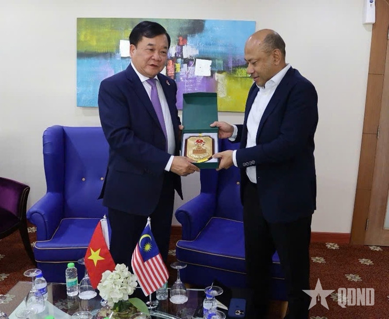 越南国防部副部长黄春战上将向马来西亚国防部副秘书长雅尼赠送纪念品。（图片来源：qdnd.vn）