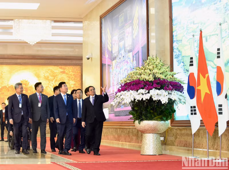 范明正总理向韩国国会议长金振杓介绍越南风土人情的图片。