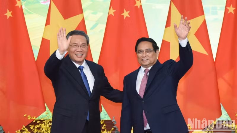 越南政府总理范明正同中国国务院总理李强向新闻媒体记者挥手致意。