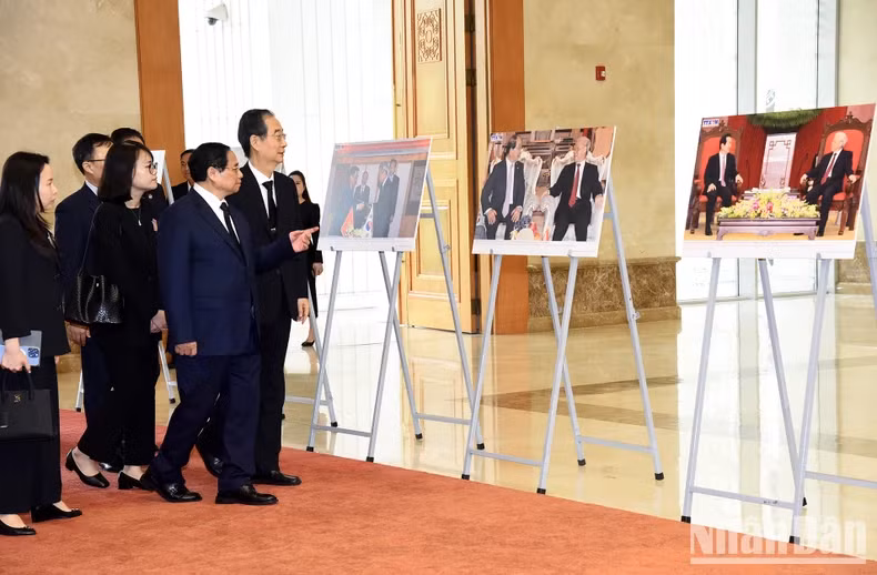 越南政府总理范明正向韩国国务总理韩德洙介绍已故总书记阮富仲对外活动的一些图片。