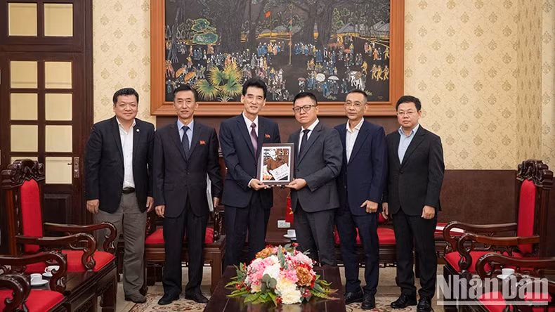 越南《人民报》社总编辑黎国明向朝鲜驻越南大使李成国送纪念品。