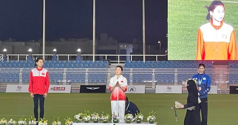 梅玉映（左侧，身穿红色运动服）站在领奖台上领奖