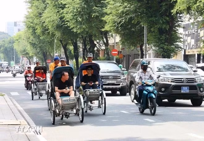 游客乘坐人力三轮车参观胡志明市中心。（图片来源：越通社）