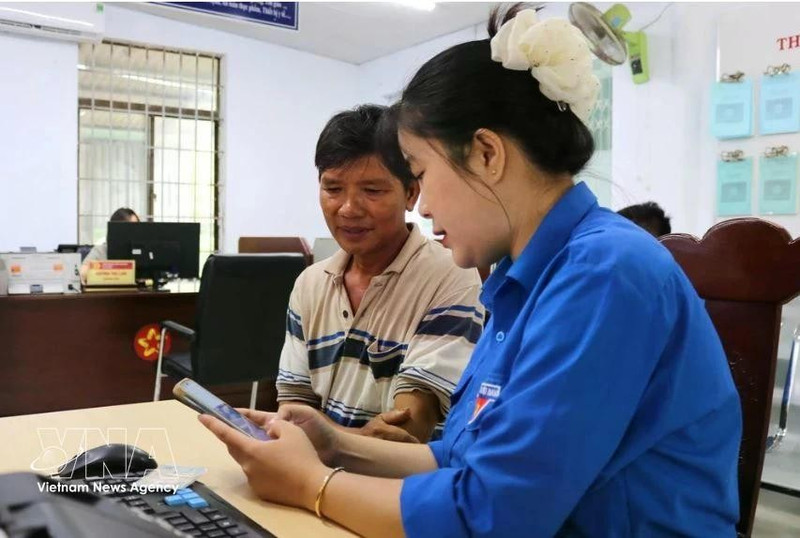 青年向河静省当地居民介绍并指导使用“i-HaTinh”数字公民应用程序的操作流程。（图片来源：越通社）