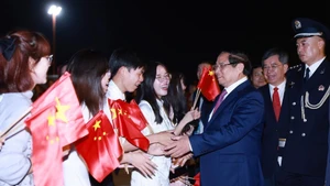 旅居中国越南人代表前来机场迎接越南政府总理范明正一行。（图片来源：越通社）