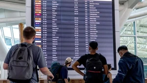旅客在印度尼西亚巴厘岛伍拉·赖国际机场查看电子显示屏上的信息。（图片来源：新华社）
