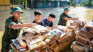 2025年，谅山省友隆民族寄宿中学遭遇历史性洪灾，部队和学生们在校外晾晒书籍。（成达 摄）