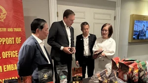 越南驻加拿大商务参赞陈秋琼向加拿大咖啡协会主席罗伯特·卡特介绍越南咖啡。（图片来源：越通社）