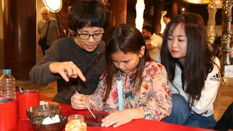 游客体验漆画艺术家的创作过程。 游客体验漆画艺术家的创作过程。