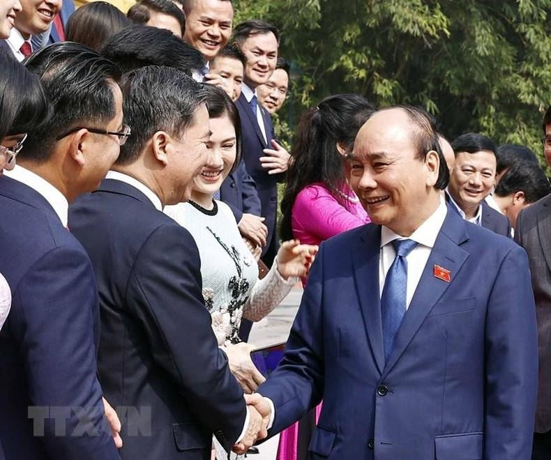 国家主席阮春福与模范青年企业家握手。