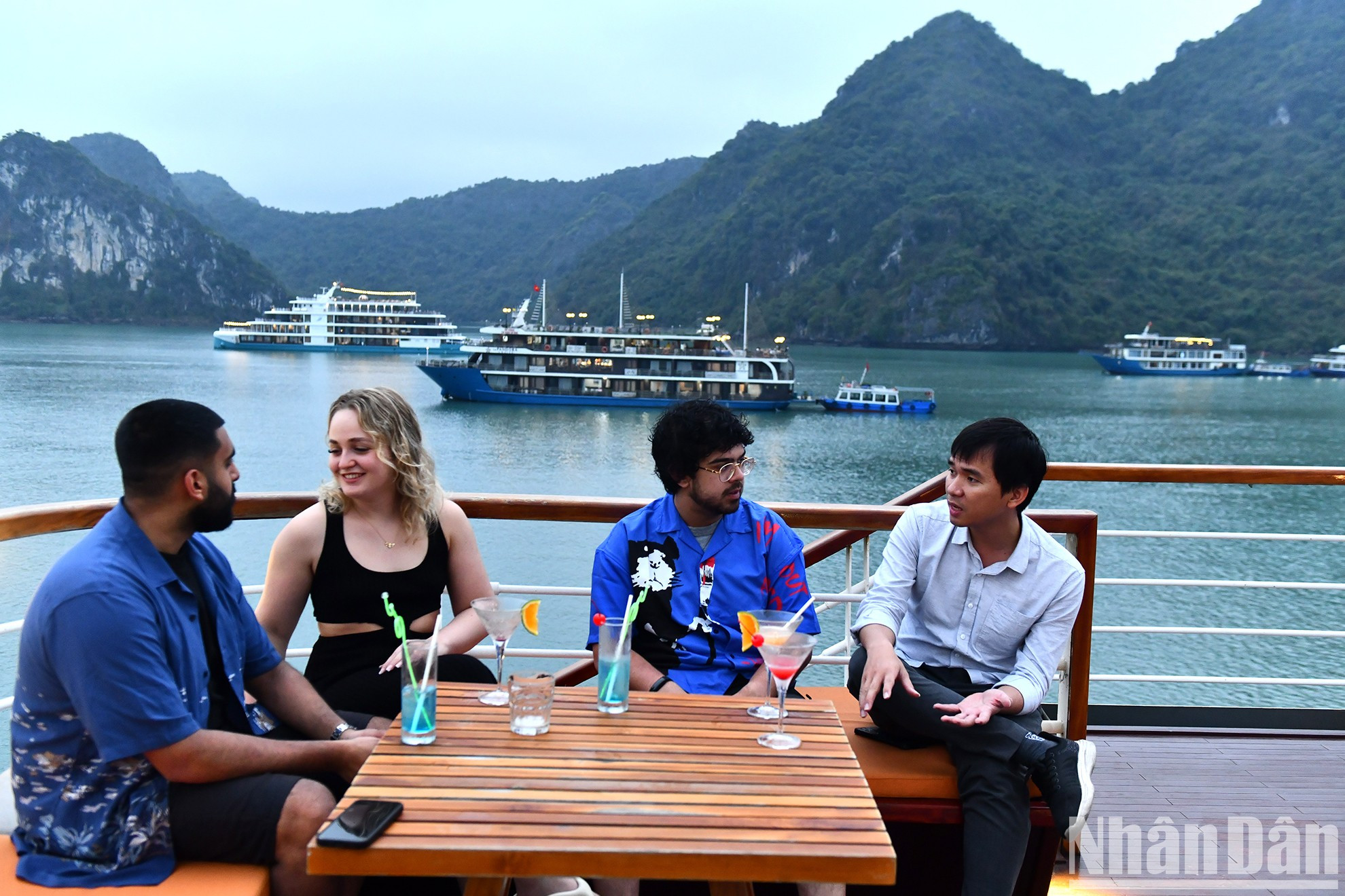 和一群朋友坐在一起,在海湾日落的美景中聊天。 和一群朋友坐在一起,在海湾日落的美景中聊天。