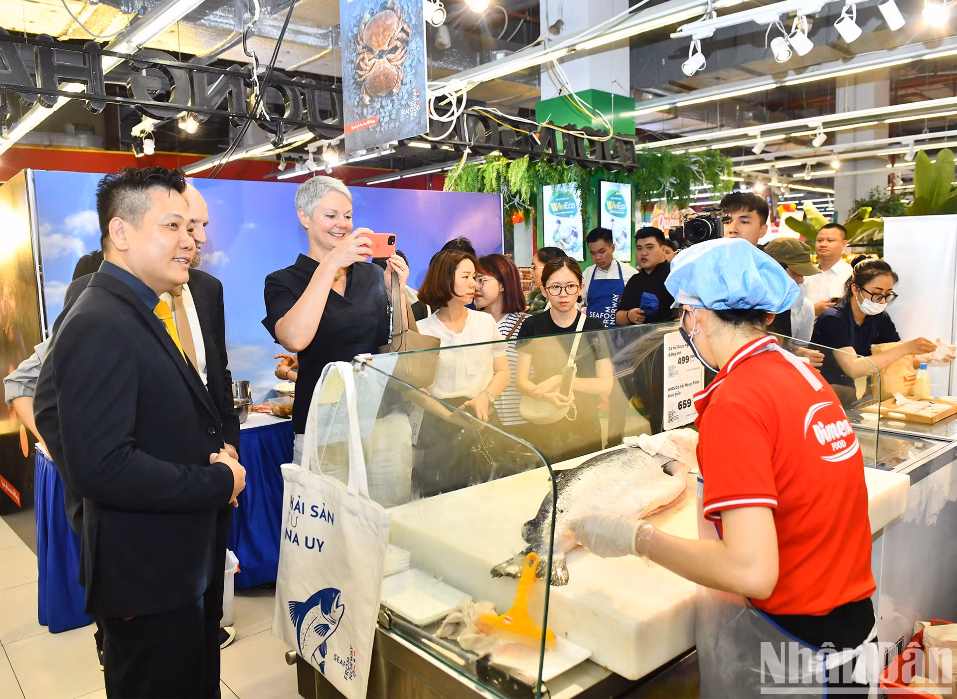希尔德·索尔巴肯大使参观WinMart超市系统中介绍挪威三文鱼产品的展位并拍照留念。
