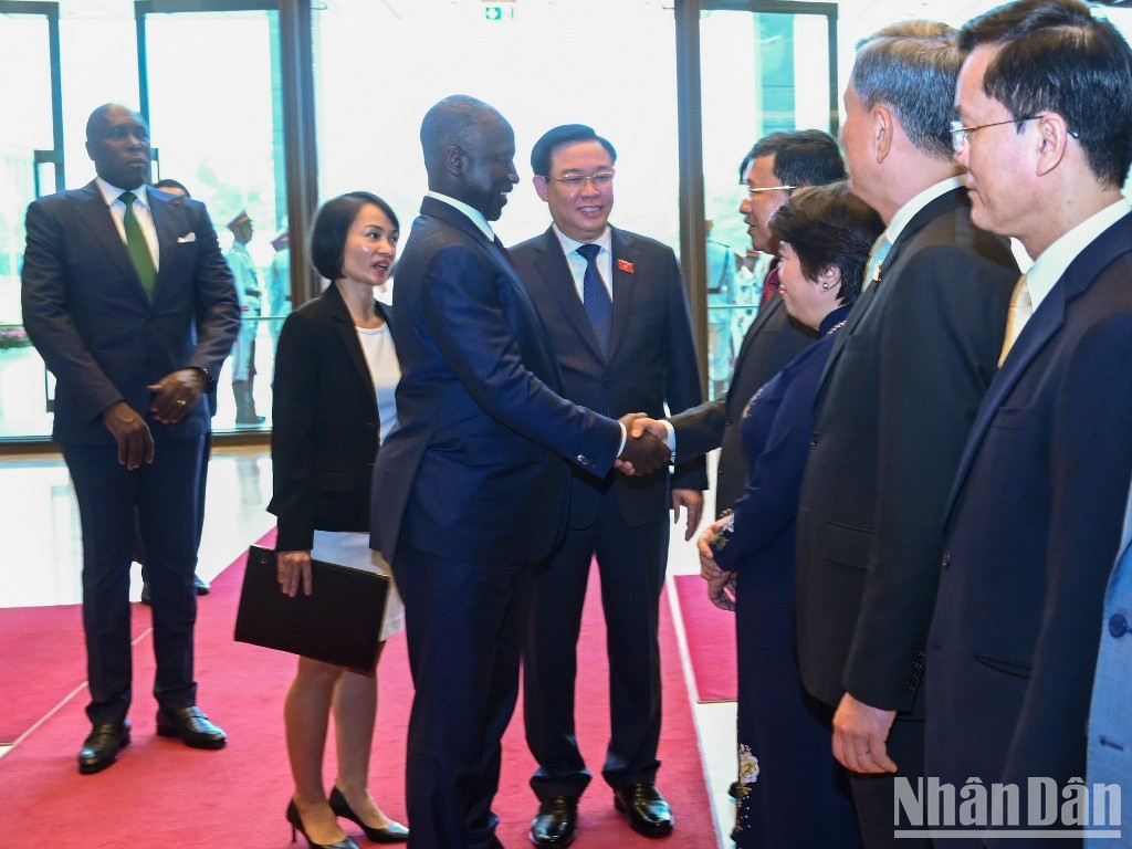 越南国会主席王廷惠向科特迪瓦国民议会议长阿达马·比克多戈介绍越南代表团成员。