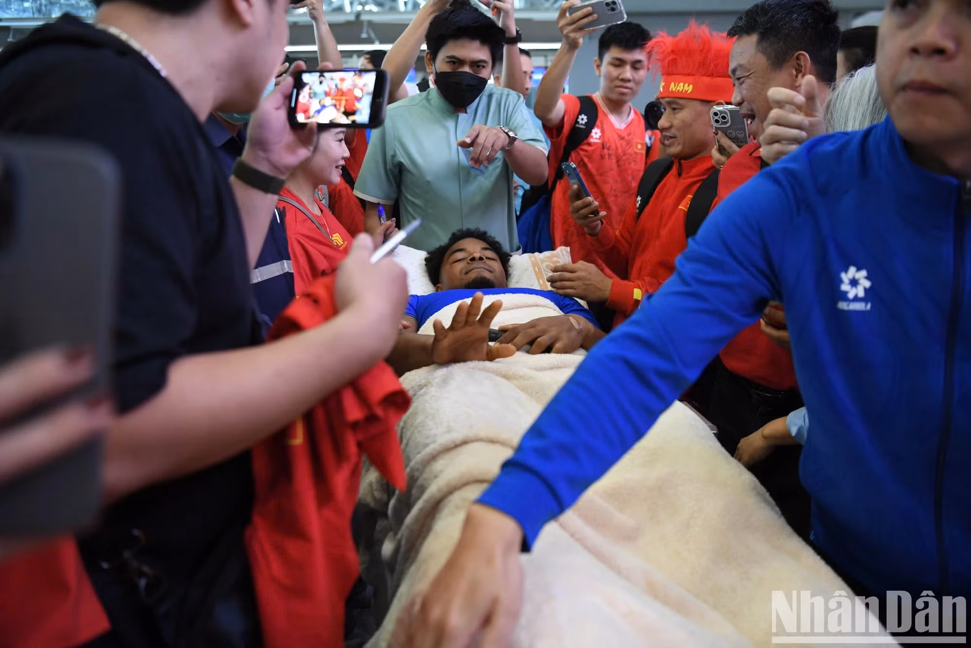 春山被担架送往机场，但仍向球迷微笑。